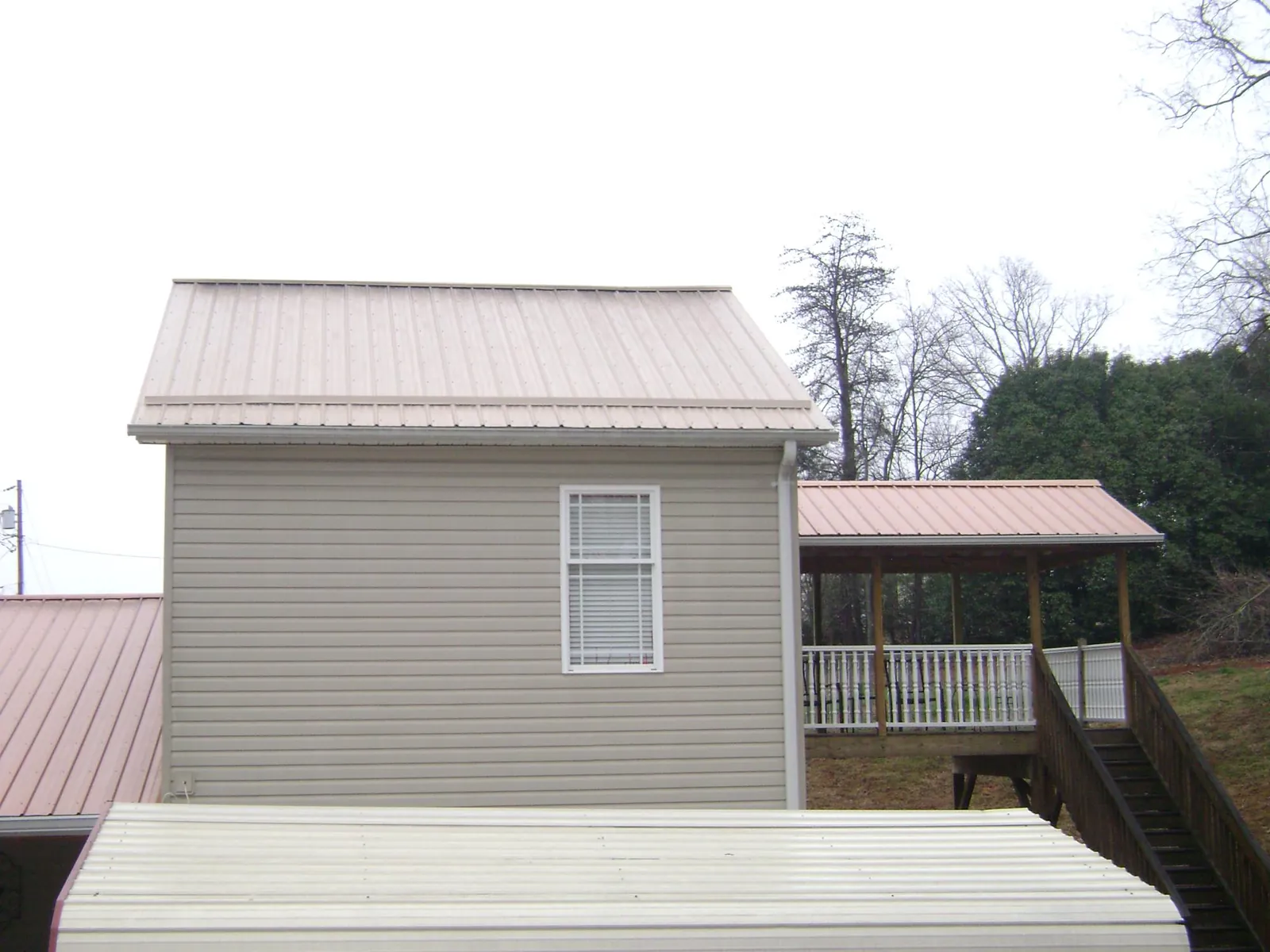 Tan metal roofs on a two story addition and attached porch, from a Roof Replacement job in Rye