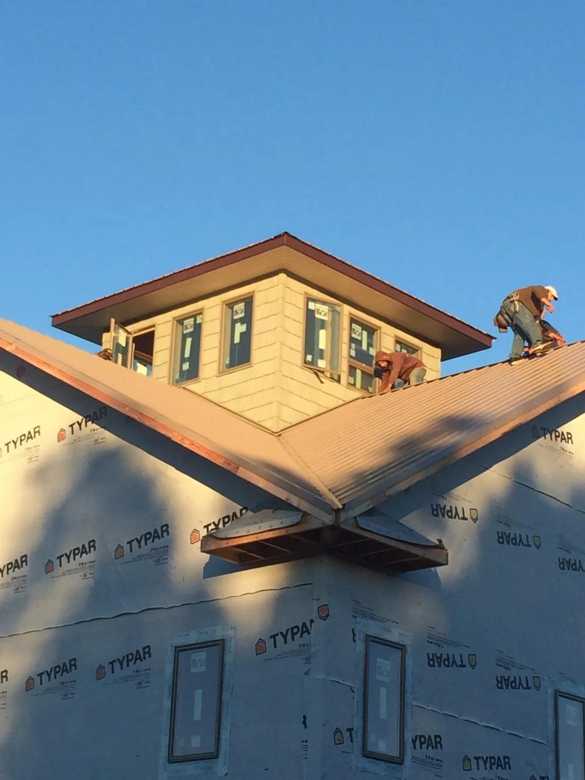 Roofers working around a rooftop cupola on a new metal roof at sunset — Roof Waterproofing in Rye by Roofing Brothers